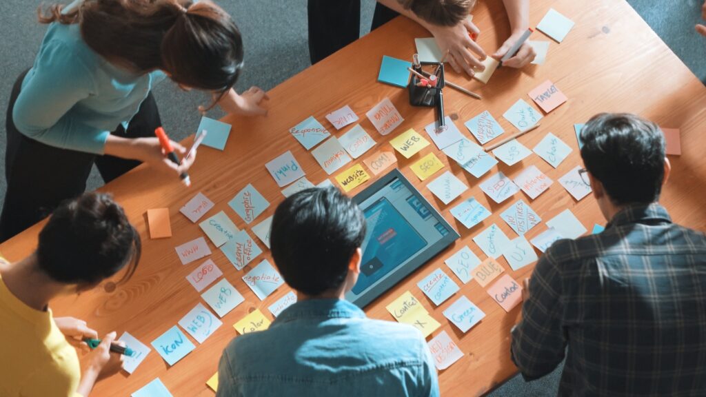 Top view of manager writing idea on sticky notes and explain idea.